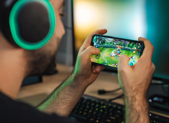 Man with headphones playing game on mobile device