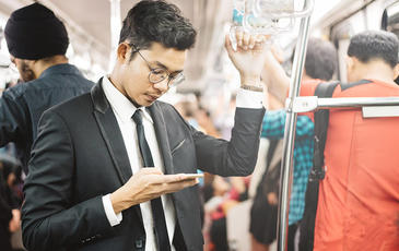 asian businessman using smarphone in a commuter train