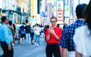 Woman in a busy city looking at her phone