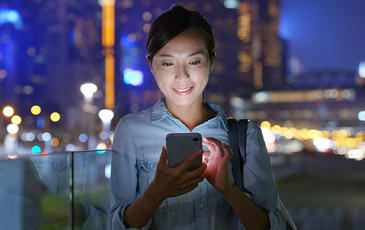 Happy Asian woman using voice, data and OTT services outdoor in a big city