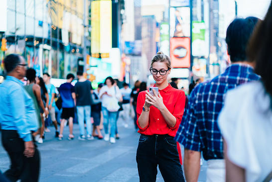Woman in a busy city looking at her phone