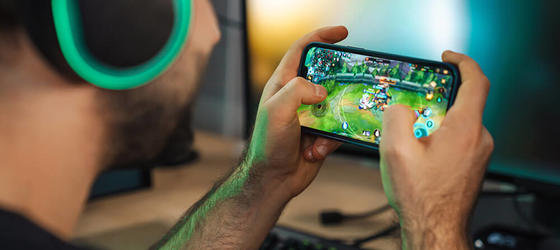 Man playing a game on mobile phone wearing headphones